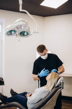 Plastic surgeon in protective gloves injecting face filler to senior woman over light studio background. Lovely mature lady getting anti-aging procedure. Aesthetic medicine concept