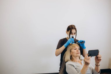 Saç ve kafa derisinin mikroskobik incelemesi için teşhis kompleksi. Bir trichologist yaşlı bir kadını muayene eder.