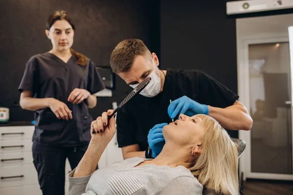 Sağlıklı gülümseyen, dişçi muayenehanesinde oturan yaşlı ve güzel bir kadın.