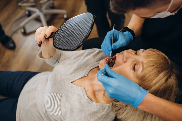 Sağlıklı gülümseyen, dişçi muayenehanesinde oturan yaşlı ve güzel bir kadın.