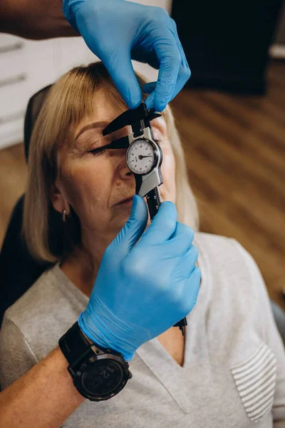 Estetik cerrahi konsültasyonunda yaşla ilgili kırışıklıkların ortadan kaldırılmasıyla ilgili yaşlı bir kadın. Gubo-chin kıvrılır, ağzın kenarları aşağı iner. Yüzün alt üçte birinin düzeltilmesi.