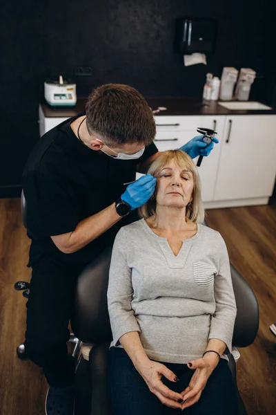 Güzellik, estetik cerrahi ve kozmetik kavramı - kadın kıdemli ve cerrah el ile mavi arka plan üzerinde şırınga