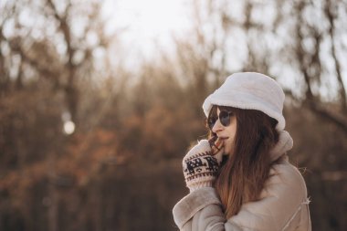 Beautiful young woman eating macaroons in the winter forest