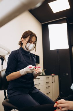 Over the shoulder view of a dentist examining a patients teeth in dental clinic. Female having her teeth examined by a dentist.
