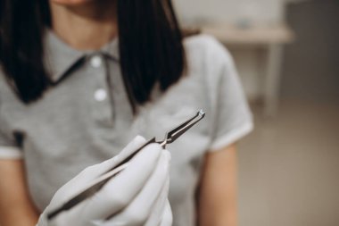 the orthodontist takes the button for braces with forceps