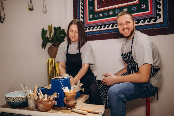 stock image handsome man and happy woman couple in love working on potter wheel while at pottery workshop. husband and wife in the kraft creative studio,young family business shop sculpts pot from clay