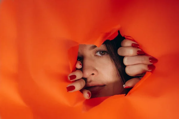 Surprise Portrait Young Caucasian Woman Looking Hole Orange Paper Distrustful — Stock Photo, Image