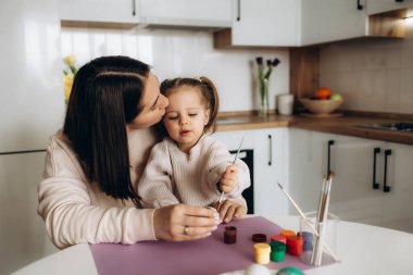 Mutlu Paskalyalar. Bir anne ve kızı Paskalya yumurtası boyuyor. Mutlu aile Paskalya için hazırlanıyor. Paskalya günü tavşan kulağı takan şirin bir kız çocuğu..