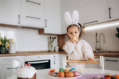 Küçük sarışın kız evde Paskalya tatili için yumurta boyama