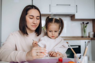 Anne ve kızı yumurtaları renklerle boyarlar. Eğlenmene bak. Mutlu aile Paskalya için hazırlanıyor..