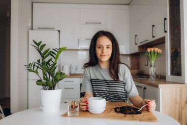 Beyaz genç kadın renkli bitkileri ile evde bazı bahçe yapıyor