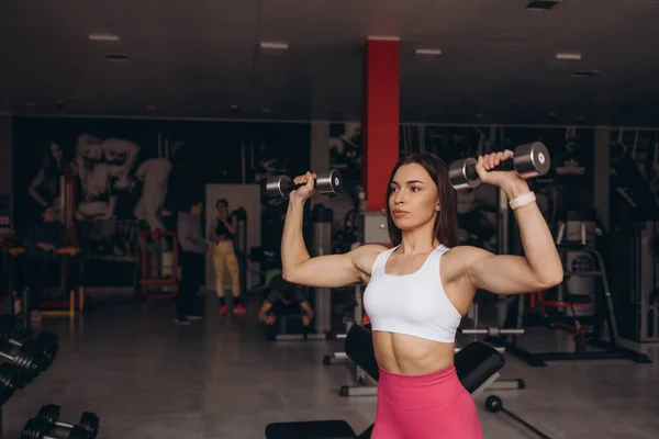 Athletic woman doing exercise for arms. Fitness model working out with dumbbells. Woman exercising with dumbbells. Fitness, workout, healthy living and diet concept.
