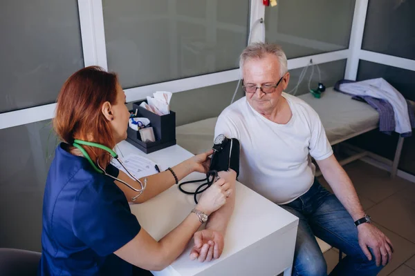 Doctor measuring blood pressure of elder man