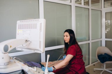 Ortopedi doktoru, klinikte hastanın dizini ultrason ile muayene ediyor.