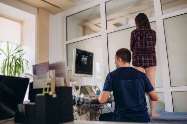 Ortopedist doktor ofisinde hastanın bacak damarlarını ultrason muayenesi yapıyor. Klinikte ultrason taramasını geçen genç bir kadın..