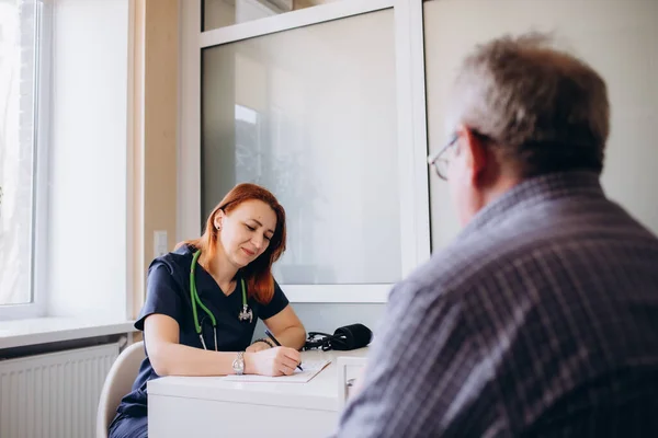 Young female professional doctor physician consulting old male patient, talking to senior adult man client at medical checkup visit. Geriatric diseases treatment. Elderly medical health care concept.
