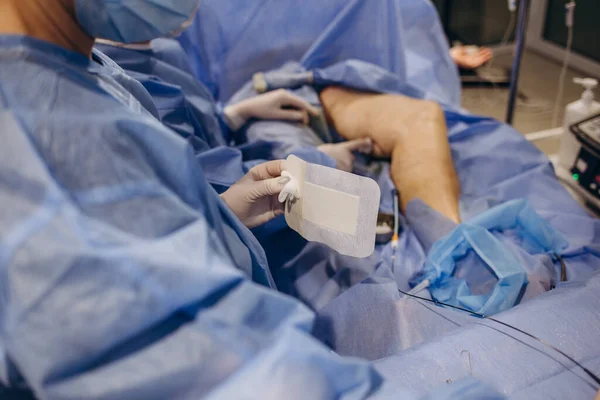 Surgeons operate on the legs of an elderly woman with varicose veins