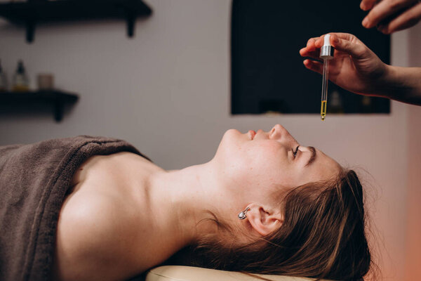 Массаж лица. Спа, курорт, красота и здоровье. Красивая женщина получает профессиональное лечение лица с питанием органическим маслом, копировальное пространство
