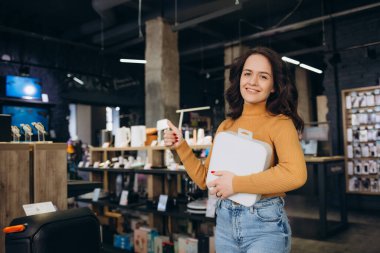 Elektronik mağazasında elinde beyaz bir kutuyla bir kadın.