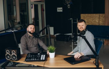 yayın stüdyosunda podcast kaydederken iki gülümseyen radyo hosts konuşma.