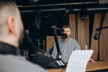 İki üniversite podcaster 'ı gülüyor ve stüdyoda iyi vakit geçiriyor. İki mutlu genç adam canlı bir ses yayını sunuyor..