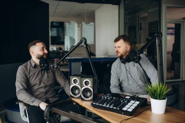 yayın stüdyosunda podcast kaydederken iki gülümseyen radyo hosts konuşma.