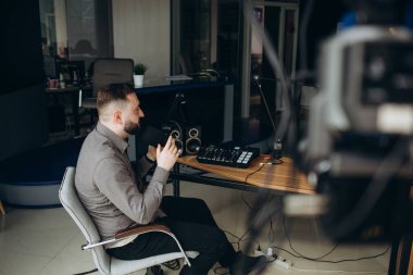 Bir radyo istasyonunda pano sunan gülümseyen İspanyol erkek radyo sunucusunun portresi.