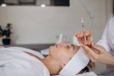 Botulinum toksin şırıngalı bir güzellik uzmanı. Kazın ayaklarını kesmek için iğne yapıyor. Yanak hacmi mezoterapiyi arttırır. Kozmetoloji kliniğinde yaşlanma önleyici tedavi ve yüz gerdirme.