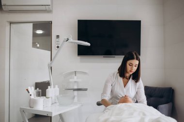 Kadın güzellik uzmanı yüzüne krem sürer. Bakım, rahatlama, gençleşme, yüz bakımı ve kozmetoloji kliniğinde pürüzsüz kırışıklıklar. Güzellik salonunda spa yapan bir kız.