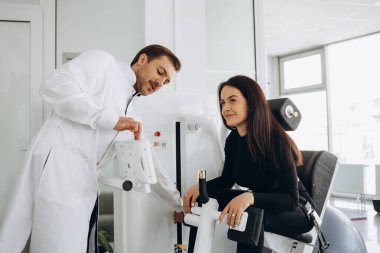 Genç bir kadın fizyoterapistle teşhis makinesinde omurga muayenesi yapıyor..