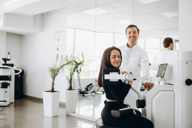 Fizyoterapist ve atletik kadın, sağlık kulübündeki fizik tedavi sırasında antrenman planları yapıyorlar.