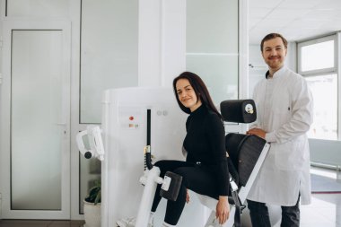 Man assisting woman training in rehabilitation center.