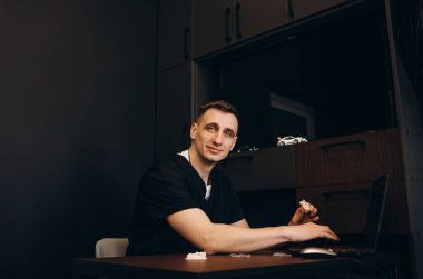 Laboratuvar önlüğü giymiş gülümseyen olgun bir doktorun portresi hastane koridorunda kolları çaprazlanmış bir şekilde duruyordu..