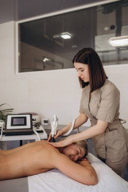Yüzündeki ve boynundaki kırışıklıkları masajla alıyor. Güzel bir sarışın, yüzünde ve boynunda kırışıklıklar var. Güzellik salonunda masaj yaptırıyor..