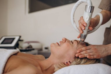 Güzellik uzmanı genç bir kızı gençleştirme için vakumlu yüz bakımı yapar. Kız güzellik uzmanının ofisinde spa tedavisi görüyor.