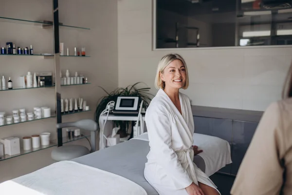 stock image Portrait of a happy woman sitting in a spa, she's wearing a white towel, after her spa day