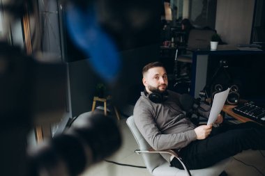 Radyo spikeri akşam talk-show 'unu sunar. Radyoda spiker olarak çalışan genç bir adam radyo stüdyosunda oturuyor ve monitöre bakıyor..