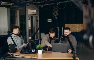 Yayın stüdyosunda podcast yapan iki radyo sunucusunun yan görüntüsü. İki neşeli radyo sunucusu stüdyoda podcast kaydediyor. Kayıt ses konsepti yapma teknolojisi.