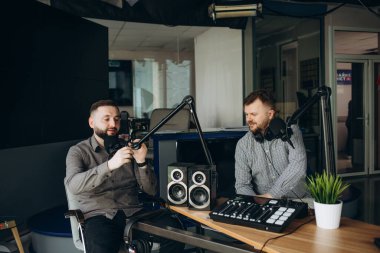 İki mutlu radyo sunucusu canlı yayında iyi vakit geçiriyor. Genç adamlar bir stüdyoda ses kaydı yaparken mutlu bir şekilde gülümsüyorlar. Neşeli içerik yaratıcıları birlikte bir internet yayını sunuyorlar.