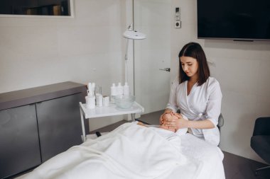 Spa, tatil köyü, güzellik ve sağlık konsepti - güzellik salonunda yüz bakımı gören güzel bir kadın