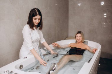 Güzellik salonunda hidroküvette oturan genç ve güzel bir kadın.