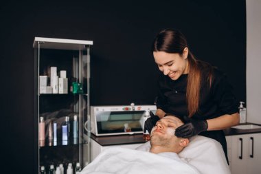 Spa salonu müşterinin yüzüne maske uygulayarak güzellik uzmanı