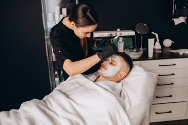 Kozmetik uzmanı insan derisine yüz için serum uygular.