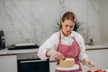 Kadın aşçı, lokanta mutfağında kahvaltıdan önce peynirli keki dekore eder..