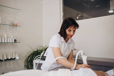 Profesyonel kozmetikçi estetik kozmetik kliniğinde donanım vücut tedavisi uyguluyor