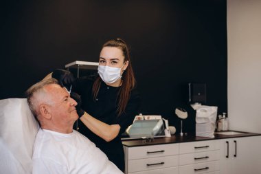 Yaşlı bir adam güzellik salonunda kırışıklıklar için iğne yapar..