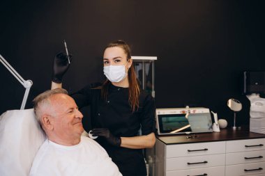 Yaşlı bir adam güzellik salonunda kırışıklıklar için iğne yapar..