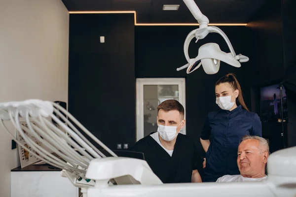 Joven Dentista Asistente Tratando Anciano —  Fotos de Stock