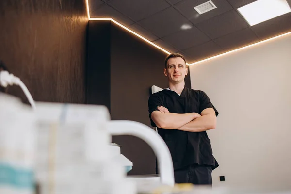 Sakallı memnun erkek fizyoterapist klinikte kafatası ve tütsü çubuklarıyla raflara bakıyor.