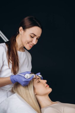 Beyaz kadın iyontoforez yaptırıyor. Yatağın üzerindeki kaplıca salonunda yüz maskesi takıyor.